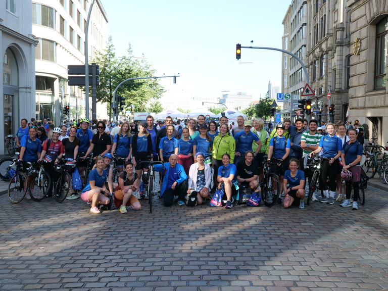 Eine Gruppe von Mitarbeiterinnen und Mitarbeitern der Immanuel Albertinen Diakonie die beim Hamburger Triathlon gestartet sind, sie tragen bunte Trikots Eine Gruppe von Mitarbeiterinnen und Mitarbeitern der Immanuel Albertinen Diakonie die beim Hamburger Triathlon gestartet sind, sie tragen bunte Trikots