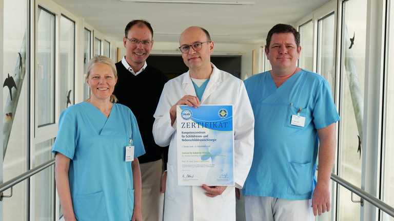 Vier Mitarbeitende des Evangelischen Amalie Sieveking Krankenhauses stehen nebeneinander und präsentieren die DGAV-Zertifizierung für das Zentrum für Endokrine Chirurgie: Dr. Denise Wittek, Geschäftsführer Andreas Schneider, Prof. Dr. Ernst von Dobschütz und Oberarzt Alexander Gnoss. Vier Mitarbeitende des Evangelischen Amalie Sieveking Krankenhauses stehen nebeneinander und präsentieren die DGAV-Zertifizierung für das Zentrum für Endokrine Chirurgie: Dr. Denise Wittek, Geschäftsführer Andreas Schneider, Prof. Dr. Ernst von Dobschütz und Oberarzt Alexander Gnoss.